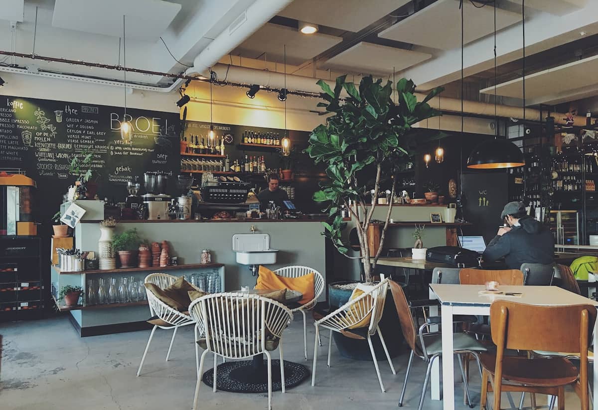 Café with a chalkboard drinks menu above the espresso counter and tables in the foreground