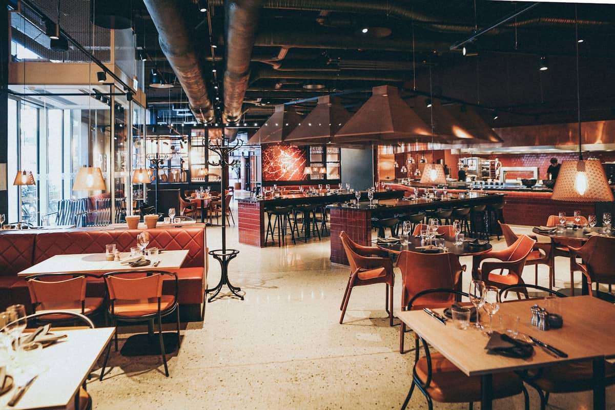 Restaurant dining room laid out for service under warm pendant lighting