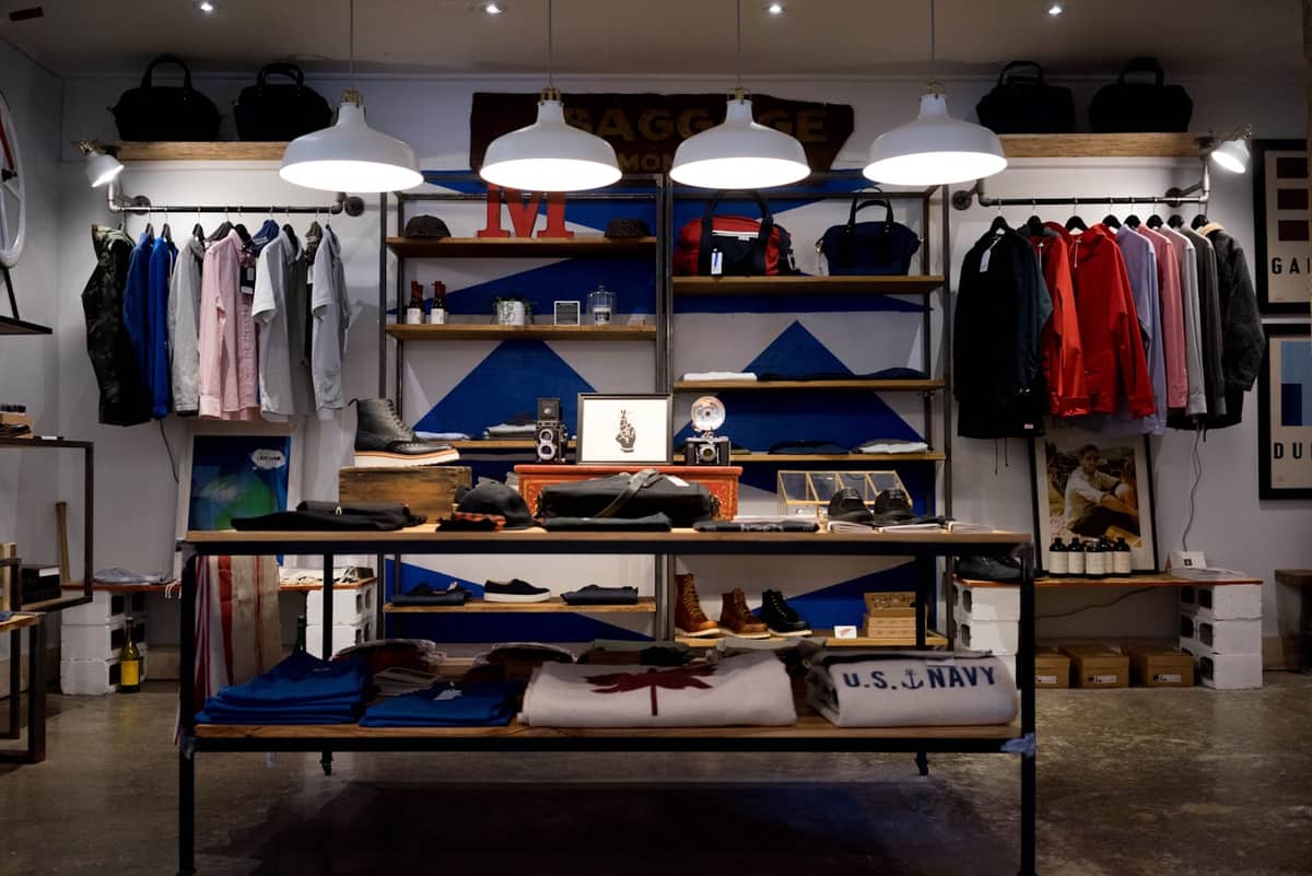 Menswear boutique with jackets on rails and a display table of folded stock